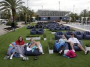 FILE - In this Thursday, June 18, 2020 file photo, people sit outdoors to watch a movie as part of a program offered by the Miami Dolphins at Hard Rock Stadium during the coronavirus pandemic in Miami Gardens, Fla. Elected officials such as Florida&#039;s governor have argued against reimposing restrictions, saying many of the newly infected are young and otherwise healthy. But younger people, too, face the possibility of severe infection and death. And authorities worry that older, more vulnerable people could be next.