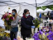 Hlee Huer, left, and Ker Chang with Cheng Blooms make bouquets at the Vancouver Farmer&#039;s Market in downtown Vancouver, June 20, 2020. Flower booths were integrated back into the farmers market last week and Chang said she is very happy to be back.