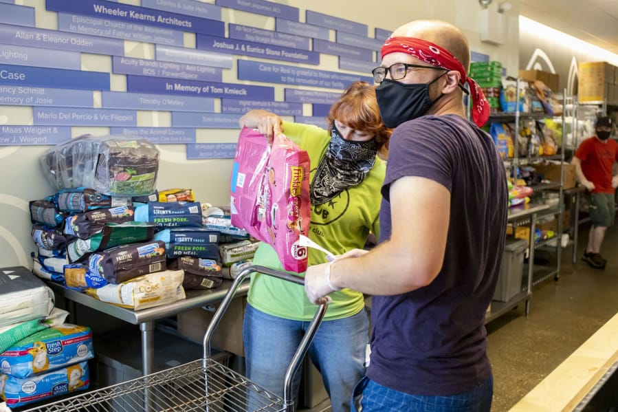 Volunteers Patti Colandrea and Stephen Klozik pack up orders for cats and dogs as the Care for Real pet food pantry reopens on July 2 in Edgewater, Ill.