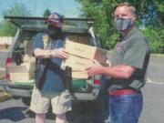 Pete Adams, right, principal officer of Vancouver Firefighters Local 452, receives two boxes of 200 face coverings from Robert Sumrill, first vice commander at Korean War Veterans Association Clark County Chapter 321.