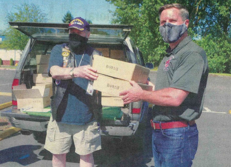 Pete Adams, right, principal officer of Vancouver Firefighters Local 452, receives two boxes of 200 face coverings from Robert Sumrill, first vice commander at Korean War Veterans Association Clark County Chapter 321.