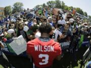 Seattle Seahawks quarterback Russell Wilson (3) signs autographs for fans following a training camp session in 2019 at Renton. The NFL is telling the Seahawks and all other teams training camps for 2020 are on. For Seattle, rookies report on July 21, and all other players on July 28. (AP Photo/Ted S.