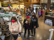 Customers line up Wednesday to check out after shopping at Chuck&#039;s Produce in Salmon Creek. Signs are posted at the entrance of the store reminding customers that face coverings are mandatory statewide.