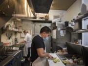 Owner Marian Adams-Manuel, background left, works with chef Vale Martinez in the busy kitchen of Frontier Public House on Tuesday. The Vancouver restaurant received Paycheck Protection Program loans to help bridge the financial gap caused by COVID-19.