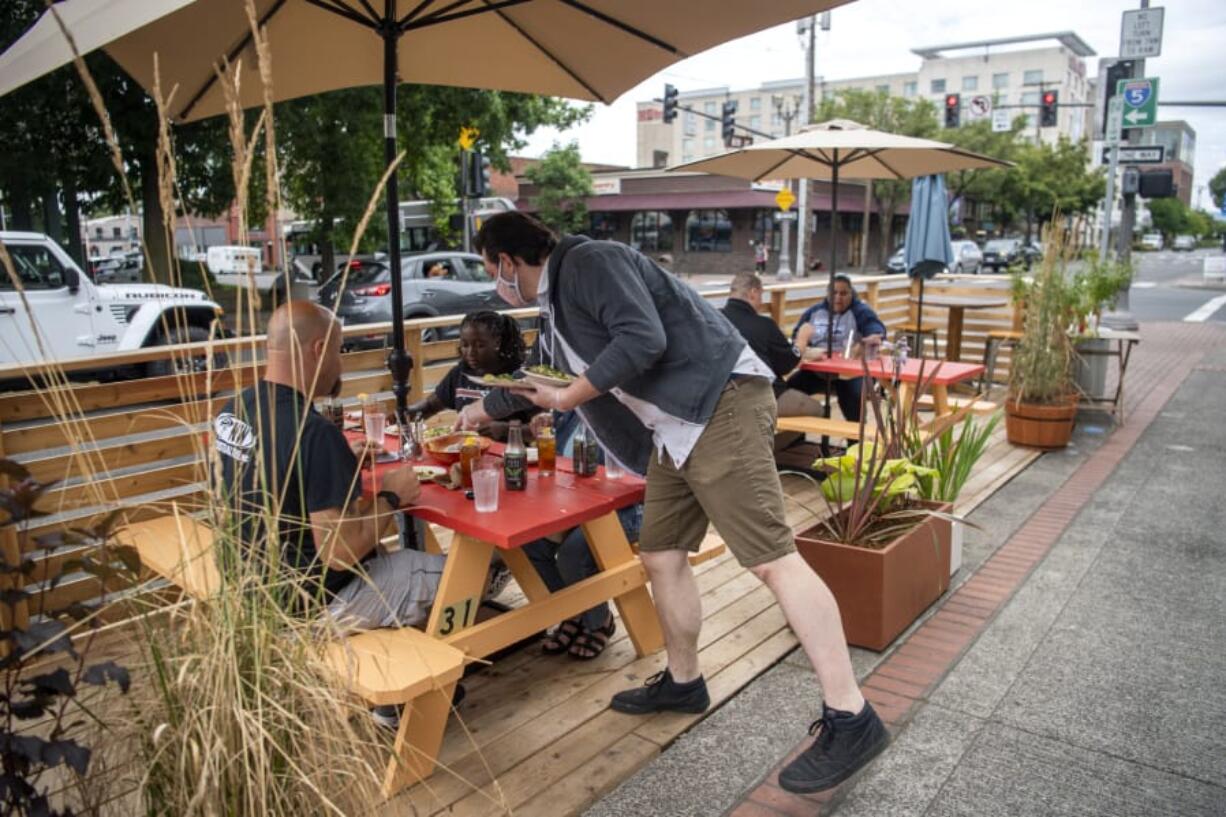 Little Conejo General Manager Keith Belter serves customers at the restaurant&#039;s new parklet -- an outdoor seating area built atop a street parking space. Vancouver began allowing restaurants to apply to create parklets last month as a way to alleviate the indoor seating restraints created by the COVID-19 pandemic.