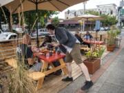 Little Conejo General Manager Keith Belter serves customers at the restaurant&#039;s new parklet -- an outdoor seating area built atop a street parking space. Vancouver began allowing restaurants to apply to create parklets last month as a way to alleviate the indoor seating restraints created by the COVID-19 pandemic.