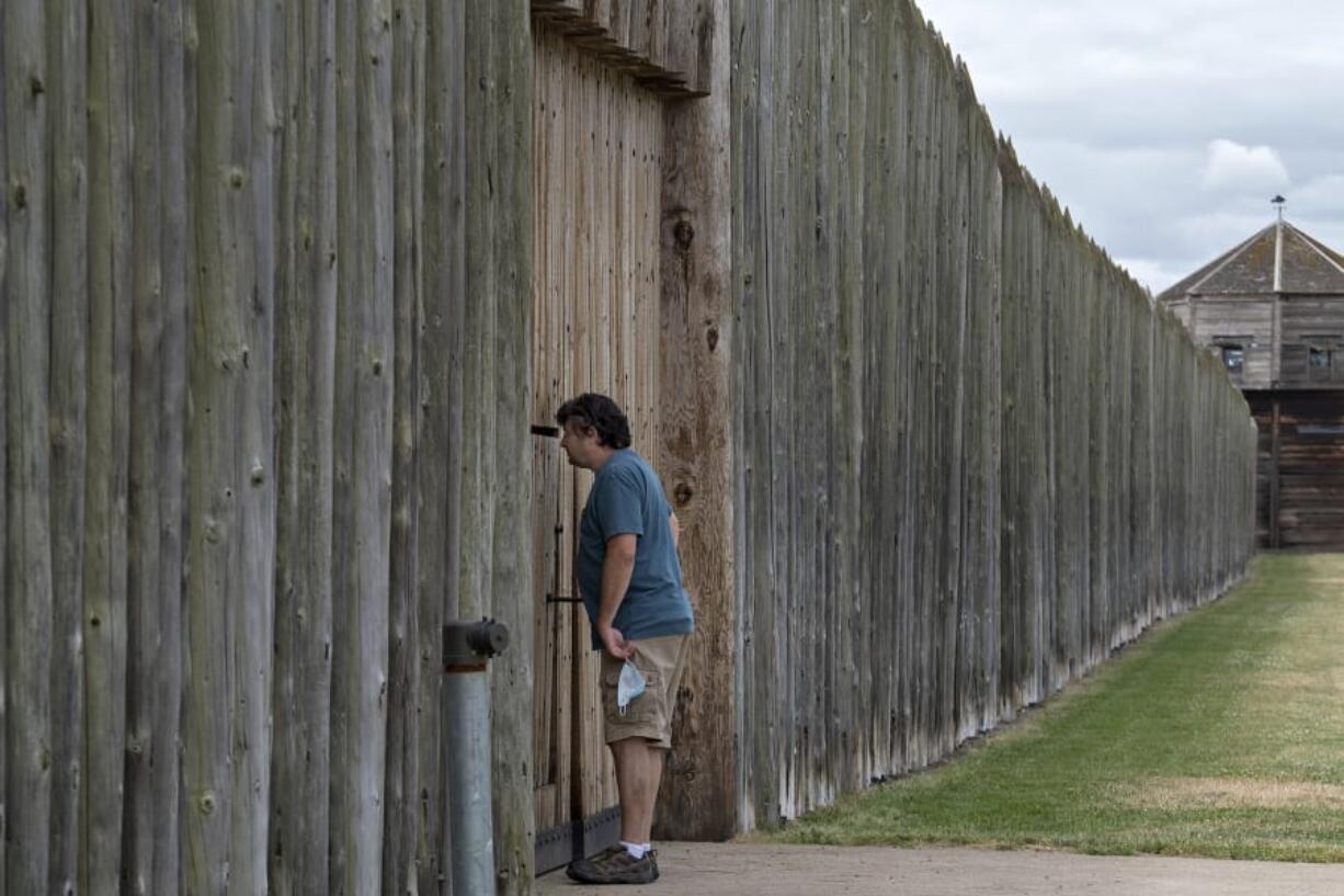 Doug Smith of Snohomish peeks through the closed front gate of the stockade at Fort Vancouver National Historic Site on Wednesday afternoon. The grounds are open, but indoor exhibits are closed.