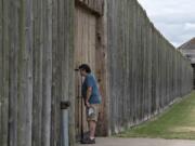 Doug Smith of Snohomish peeks through the closed front gate of the stockade at Fort Vancouver National Historic Site on Wednesday afternoon. The grounds are open, but indoor exhibits are closed.