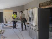 Luke Schlecht, left, and William Jones of Foxbrigade LLC lend a hand to the renovation of a kitchen at a home in Salmon Creek. Local contractors say common home areas like kitchens, family rooms, finished basements and covered patios are all in high demand while families are stuck at home during the COVID-19 pandemic.