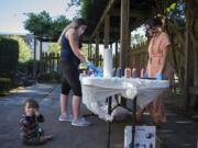 Carter Campbell, 8 months, from left, joins his mom, Breeanna Campbell, as she creates a colorful tie-dye shirt with the help of Julie Tappan, independent living skills resource specialist, at the YWCA on Tuesday evening. The summer celebration was for young people who are participating in YWCA Clark County&#039;s Independent Living Skills program. These youth have all aged out of the foster care system and are learning to live on their own.