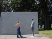 Camas High School rising seniors Kiana Gouveia, left, and Eli McMillan, both 17, pause to chat Tuesday afternoon at Crown Park. The pair had been writing messages on the wall in chalk to support the Black Lives Matter movement, but the murals have repeatedly been removed.