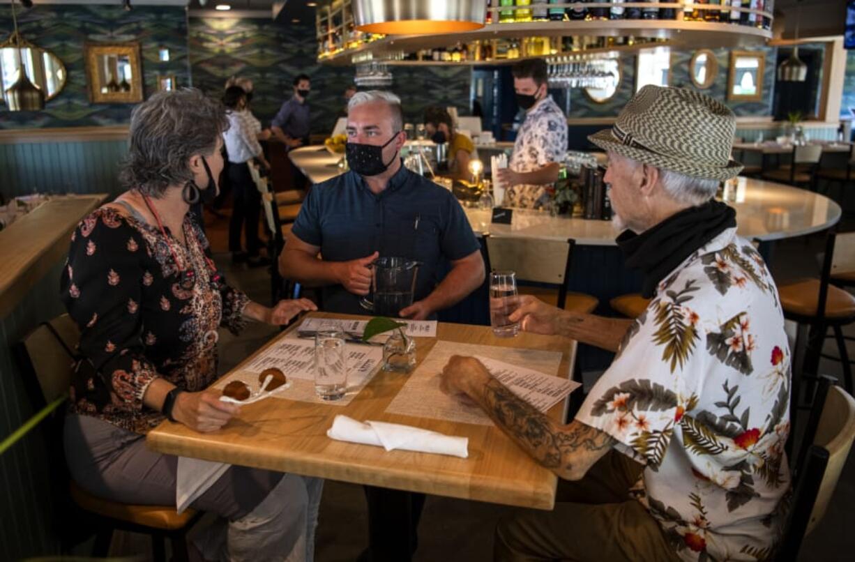 Bartender Derek Devlin, center, takes an order from Marliese Franklin and Jerry Ames during a soft-opening lunch at the second location of Amaro&#039;s Table in Hazel Dell. The restaurant&#039;s official opening is scheduled for Monday.