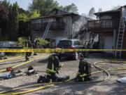 Caution tape surrounds the scene as firefighters battle a blaze in two adjoining duplexes on Olive Street on Friday morning, July 31, 2020.