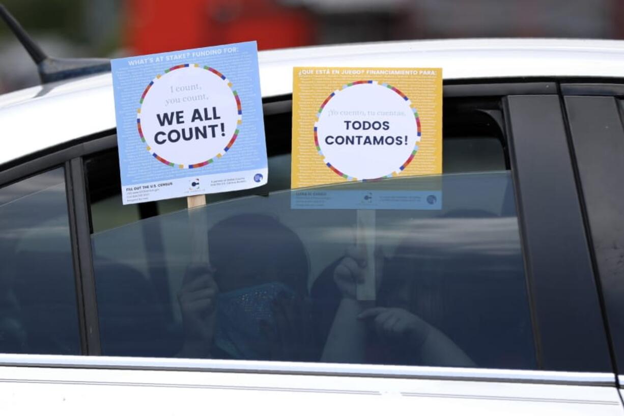 FILE - In this June 25, 2020, file photo, two young children hold signs through the car window that make reference to the 2020 U.S. Census as they wait in the car with their family at an outreach event in Dallas.