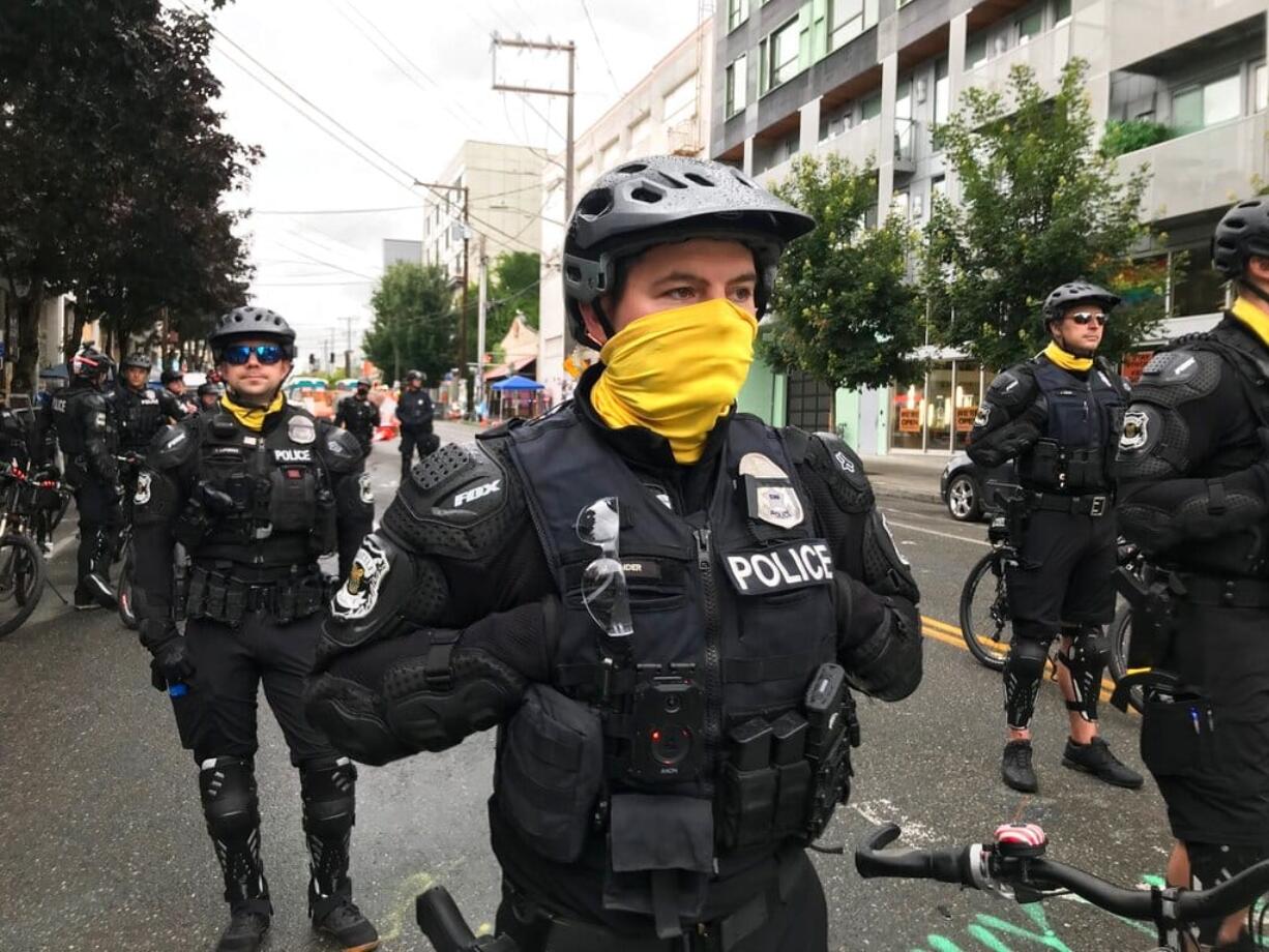 Seattle police stand on a road in the Capitol Hill Organized Protest zone early Wednesday, July 1, 2020. Police in Seattle have torn down demonstrators' tents in the city's so-called occupied protest zone after the mayor ordered it cleared.