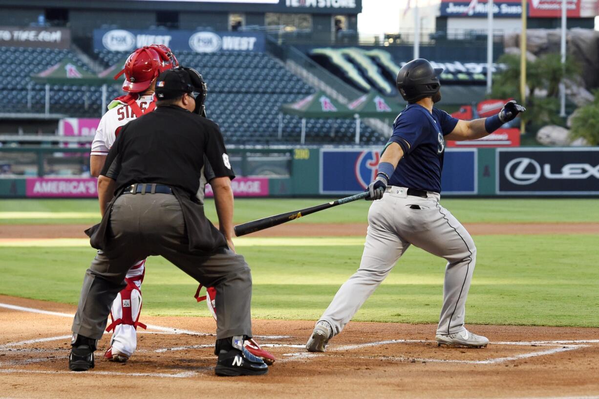 Seattle Mariners' Jose Marmolejos, right, hits a three-run home run as Los Angeles Angels catcher Max Stassi, left, watches along with home plate umpire Doug Eddings during the first inning of a baseball game Thursday, July 30, 2020, in Anaheim, Calif. (AP Photo/Mark J.