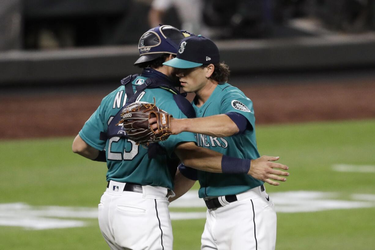 Seattle Mariners closing pitcher Taylor Williams, right, embraces catcher Austin Nola after the team beat the Oakland Athletics in a baseball game during the Mariners home opener Friday, July 31, 2020, in Seattle.