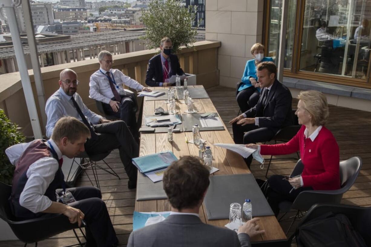 European Council President Charles Michel, center left, speaks with German Chancellor Angela Merkel, third right, French President Emmanuel Macron, second right, and European Commission President Ursula von der Leyen, right, during a meeting on the sidelines of an EU summit at the European Council building in Brussels, Saturday, July 18, 2020. Leaders from 27 European Union nations met face-to-face for a second day of an EU summit to assess an overall budget and recovery package spread over seven years estimated at some 1.75 trillion to 1.85 trillion euros.