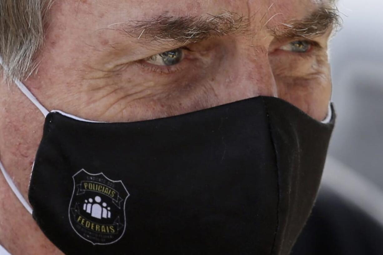 FILE - In this May 26, 2020 file photo, Brazil&#039;s President Jair Bolsonaro, wearing a face mask with a logo of the Federal Police, leaves his official residence of Alvorada Palace in Brasilia, Brazil. Bolsonaro won the presidency in 2018 with a campaign that emphasized law and order, and said police should be able to kill criminals with almost no legal constraints in order to curb homicides.