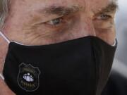 FILE - In this May 26, 2020 file photo, Brazil&#039;s President Jair Bolsonaro, wearing a face mask with a logo of the Federal Police, leaves his official residence of Alvorada Palace in Brasilia, Brazil. Bolsonaro won the presidency in 2018 with a campaign that emphasized law and order, and said police should be able to kill criminals with almost no legal constraints in order to curb homicides.