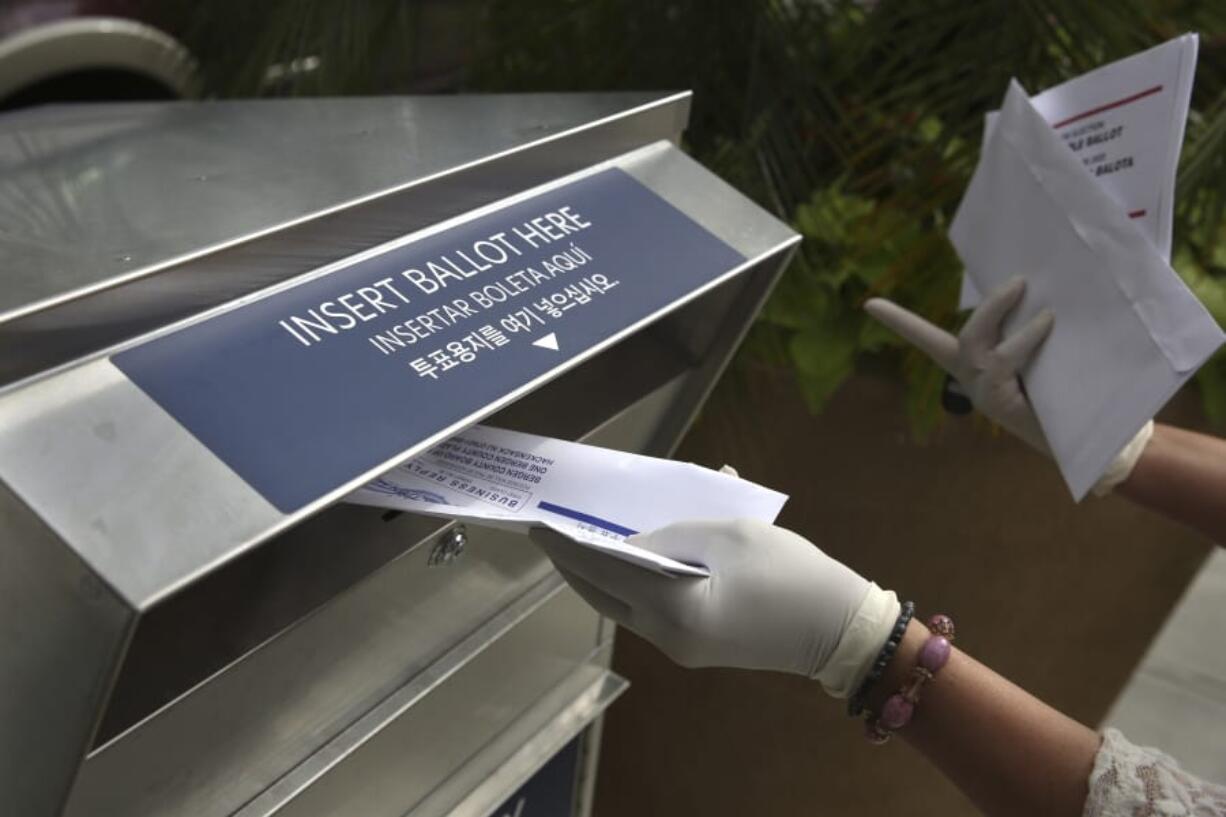 FILE - In this July 7, 2020, file photo a woman wearing gloves drops off a mail-in ballot at a drop box in Hackensack, N.J. After months of hearing President Donald Trump denigrate mail-in balloting, Republicans in the critical battleground state now find themselves far behind Democrats in the perennial push to urge their voters to vote remotely. While Democrats have doubled the number of their voters who&#039;ve asked for a mail ballot compared to 2016, Republicans have only increased by about 20% since the same time.