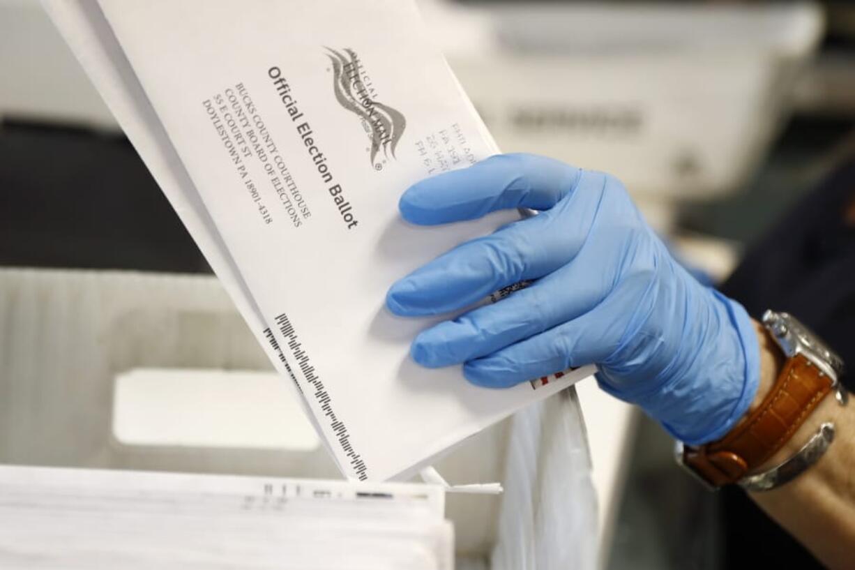 FILE - In this May 27, 2020 file photo, a worker processes mail-in ballots at the Bucks County Board of Elections office prior to the primary election in Doylestown, Pa. Deep-pocketed and often anonymous donors are pouring over $100 million into an intensifying dispute about whether it should be easier to vote by mail, a fight that could determine President Donald Trump&#039;s fate in the November election.