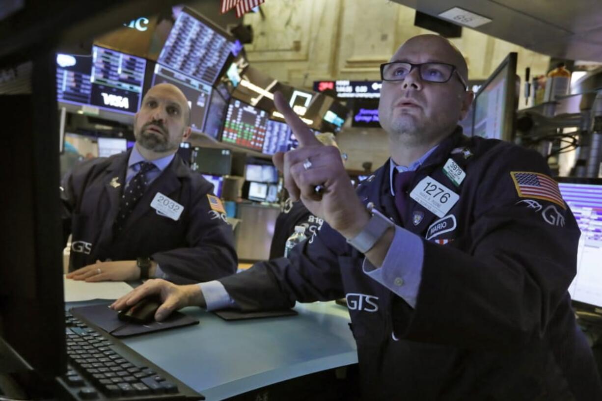 FILE - In this Tuesday, March 10, 2020, file photo, specialists James Denaro, left, and Mario Picone work on the floor of the New York Stock Exchange. Global stock markets and Wall Street futures rose Thursday, July 2, 2020, on hopes for the development of a coronavirus vaccine and ahead of the release of monthly U.S. jobs data.