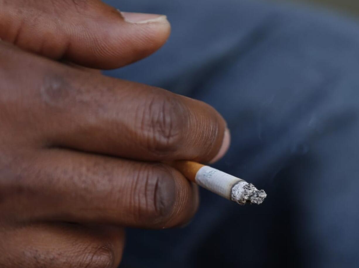 FILE - In this Sept. 17, 2015 file photo, a smoker holds his cigarette outside Oklahoma County Courthouse in Oklahoma City. A federal health panel wants to widen the number of Americans who get yearly scans for lung cancer, by opening the screening to less-heavy smokers. Lung cancer is the nation&#039;s top cancer killer, causing more than 135,000 deaths in the U.S. each year. Smoking is the chief cause and quitting is the best protection.