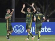 Portland Timbers midfielder Diego Valeri (8) celebrates after scoring a goal as midfielder Sebastian Blanco, left, and defender Jorge Villafana (4) come to congratulate him during the second half of an MLS soccer match against the Houston Dynamo, Saturday, July 18, 2020, in Kissimmee, Fla. (AP Photo/Phelan M.