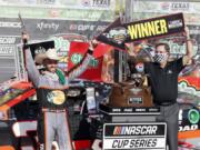 Texas Motor Speedway President and General Manager Eddie Gossage, right, holds a &quot;winner&quot; sign as Austin Dillon, left, celebrates by firing six shooters after winning the NASCAR Cup Series auto race at Texas Motor Speedway in Fort Worth, Texas, Sunday, July 19, 2020.