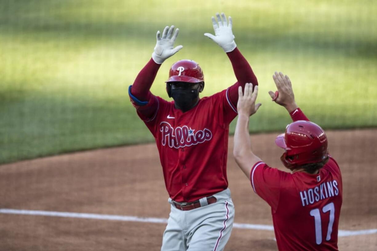 Philadelphia Phillies&#039; Didi Gregorius celebrates without touching, while wearing a mask, his three-run homer with Rhys Hoskins during the first inning of an exhibition baseball game against the Washington Nationals at Nationals Park, Saturday, July 18, 2020, in Washington.