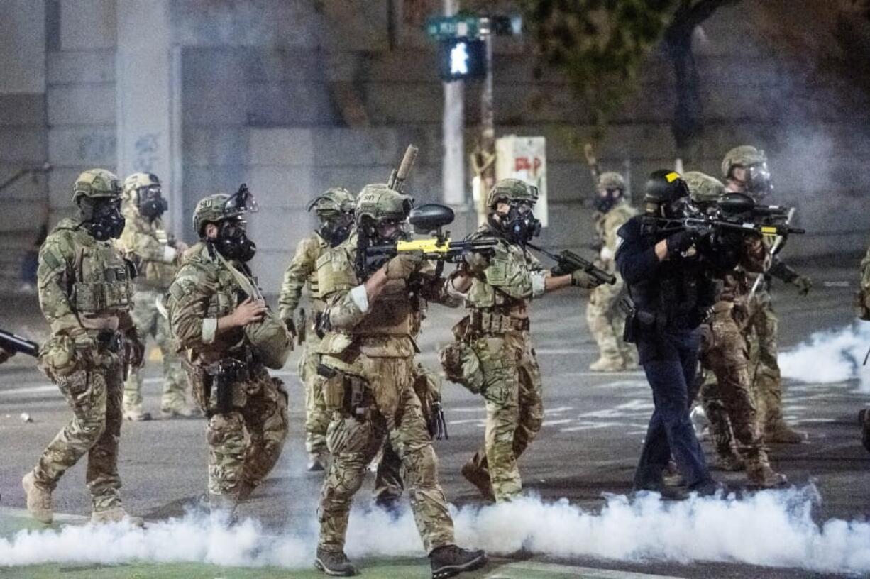 FILE - In this July 20, 2020 file photo Federal agents use crowd control munitions to disperse Black Lives Matter protesters at the Mark O. Hatfield United States Courthouse in Portland, Ore. When armed protesters took over a remote wildlife refuge in eastern Oregon four years ago to oppose federal control of public lands, U.S. agents negotiated with the conservative occupiers for weeks while some state leaders begged for stronger action. This month, federal officers sent to Portland to quell chaotic protests against racial injustice took swift and, some say, harsh action: launching tear gas, firing less-lethal ammunition and helping arrest more than 40 people in the first two weeks.