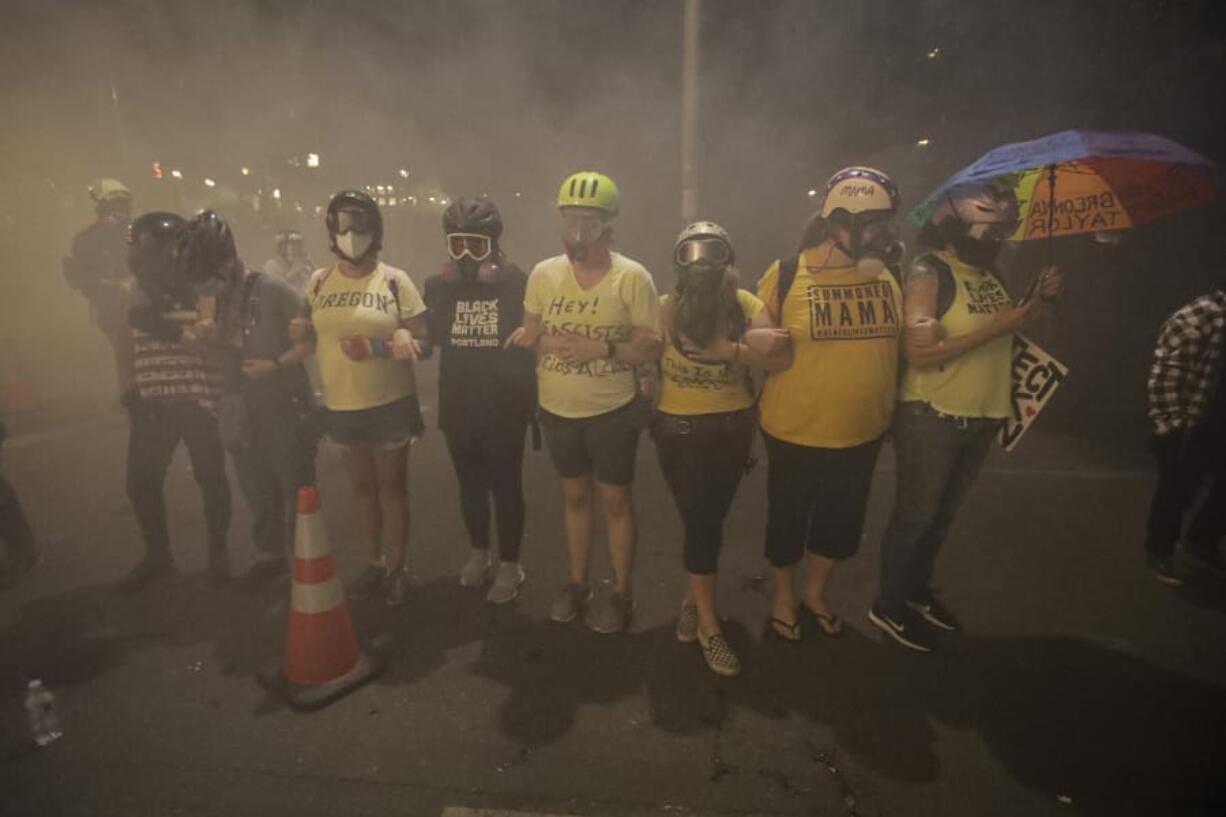 Members of the &#039;Wall of Moms&#039; protest group lock arms as they are tear-gassed by federal officers during a Black Lives Matter protest at the Mark O. Hatfield United States Courthouse Monday, July 27, 2020, in Portland, Ore.