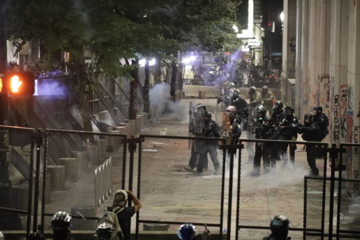 Federal officers walk out in formation to launch tear gas at demonstrators during a Black Lives Matter protest at the Mark O. Hatfield United States Courthouse Sunday, July 26, 2020, in Portland, Ore.