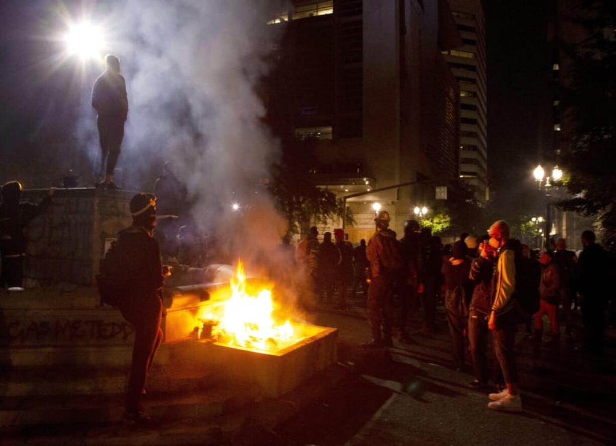 FILE - In this July 4, 2020, file photo, protesters gather near a fire in downtown Portland, Ore. Oregon&#039;s largest city is in crisis as violent protests have wracked downtown for weeks. The mayor can&#039;t bring the council along on cracking down because of very liberal council members and no matter what he does, the city gets sued anyway. Meanwhile, downtown businesses are being destroyed on top of the pandemic and the rank-and-file police are increasingly venting their frustration.