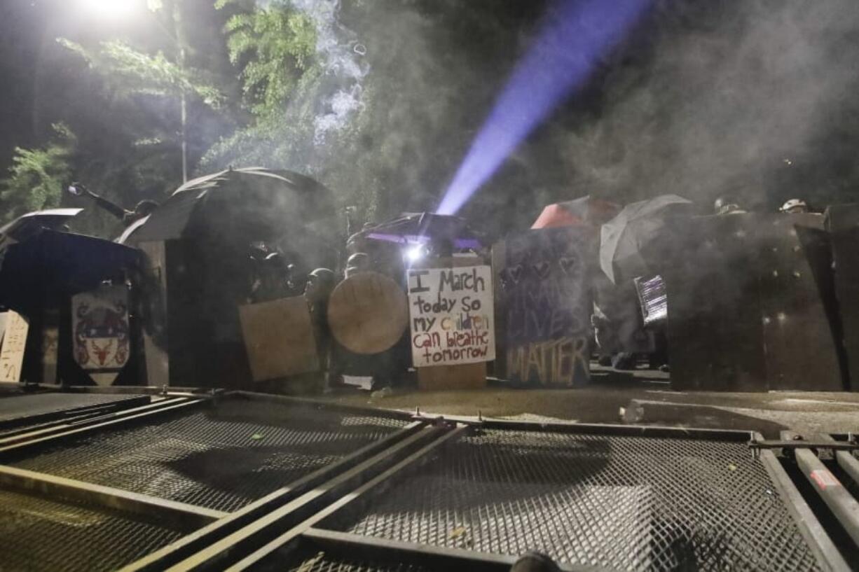 Demonstrators shield themselves behind a toppled fence as federal officers deploy tear gas during a Black Lives Matter protest at the Mark O. Hatfield United States Courthouse Sunday, July 26, 2020, in Portland, Ore.