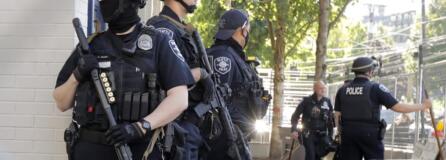 Seattle Police officers hold weapons as they stand guard outside the East Precinct Building, Sunday, July 19, 2020 in Seattle. Protesters broke windows at the building earlier in the afternoon. (AP Photo/Ted S.