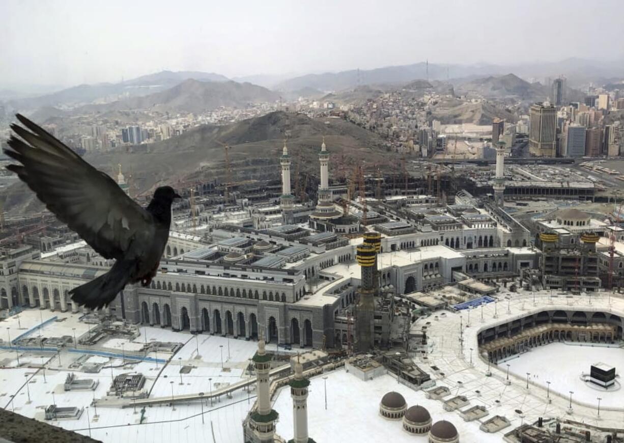 A pigeon flies over the site of the Grand Mosque that is empty due to the coronavirus prevention procedures, on the first day of the annual hajj that normally draws millions of faithful, in the Muslim holy city of Mecca, Saudi Arabia, Wednesday, July 29, 2020. A unique and scaled-down hajj started on Wednesday.