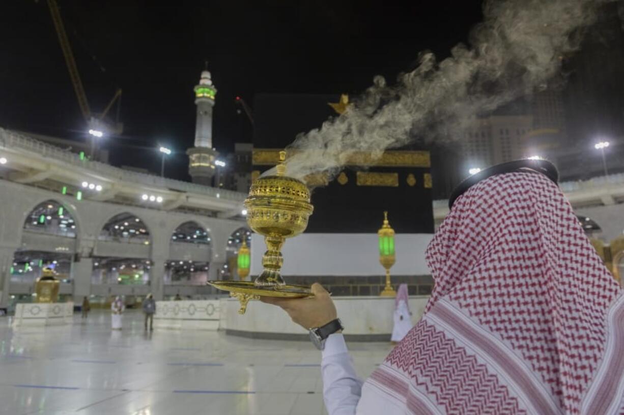 A man burns incense as the area around the Kaaba, the square structure in the Great Mosque, toward which believers turn when praying, is prepared for pilgrims, in Mecca, Saudi Arabia, late Sunday, July 26, 2020. Anywhere from 1,000 to 10,000 pilgrims will be allowed to perform the annual hajj pilgrimage this year due to the virus pandemic.