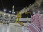 A man burns incense as the area around the Kaaba, the square structure in the Great Mosque, toward which believers turn when praying, is prepared for pilgrims, in Mecca, Saudi Arabia, late Sunday, July 26, 2020. Anywhere from 1,000 to 10,000 pilgrims will be allowed to perform the annual hajj pilgrimage this year due to the virus pandemic.