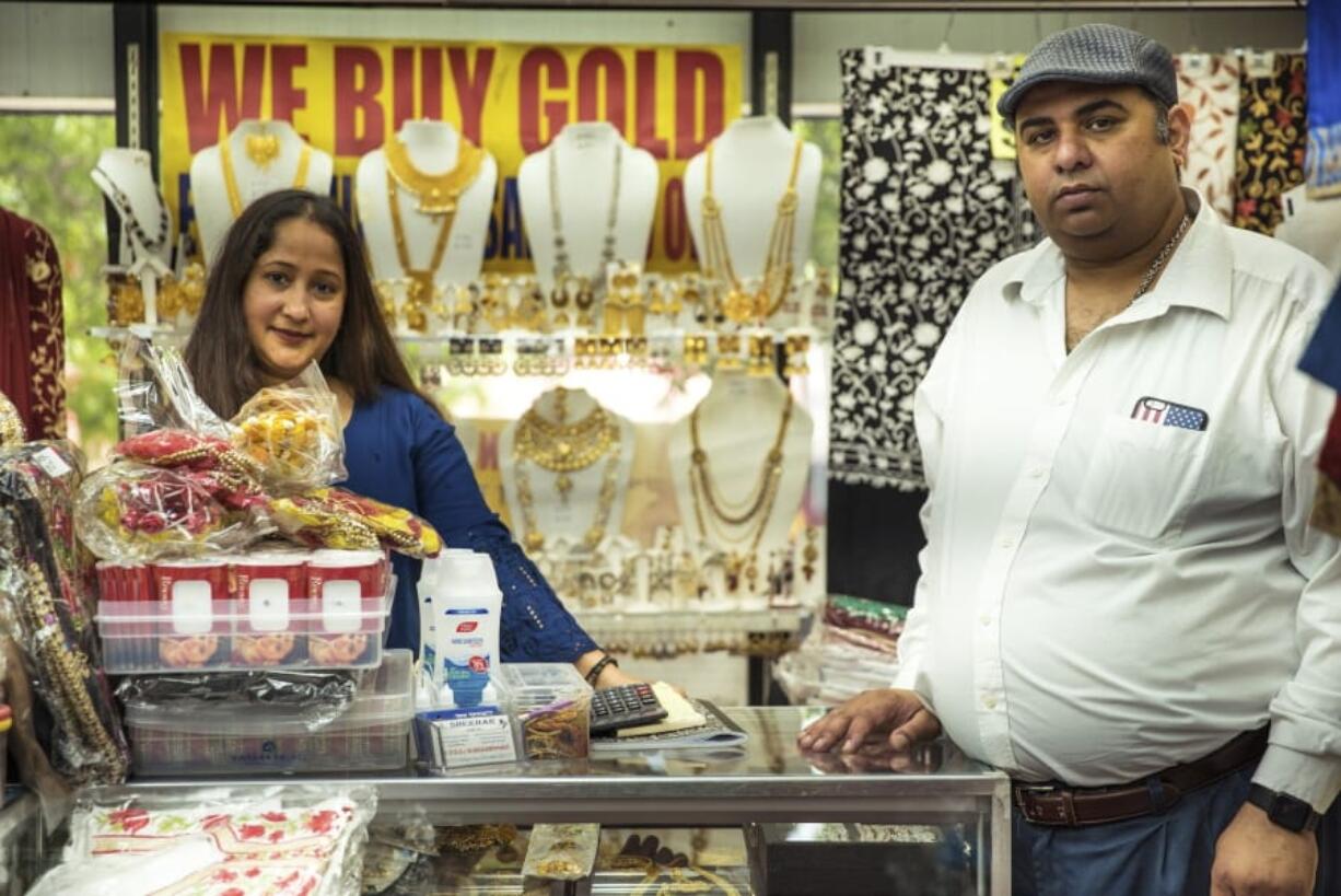 Lolith Lima Rodrigues, left, and Chander Shekhar, co-owners of Shopno Fashion in New York&#039;s Jackson Heights neighborhood, pose for a portrait on June 22, 2020, the first day of New York City&#039;s &quot;Phase Two&quot; reopening plan. This neighborhood was hit particularly hard by COVID-19, and as shops opened for the first time in more than three months, no one knew what lay ahead.