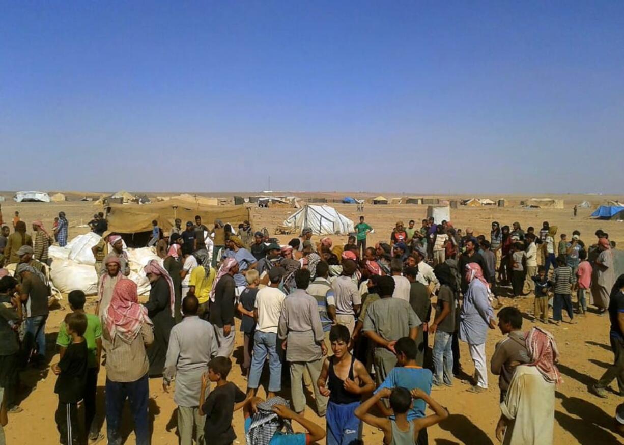 FILE - In this Aug. 4, 2016 file photo, people gather to take basic food stuffs and other aid from community leaders charged with distributing equitably the supplies to the 64,000-person refugee camp called Ruqban on the Jordan-Syria border. Over the last two days, members of the UN Security Council have been haggling over cross-border aid delivery to Syria, with Russia, a major ally of the Syria government, working to reduce the delivery of U.N. humanitarian aid to Syria&#039;s last rebel-held northwest down from two crossings to just one. A final vote is expected Friday, July 10, 2020 as western countries push on a new resolution to keep the two crossings open for six months, instead of a year.