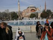 People walk in 2017 backdropped by the Byzantine-era Hagia Sophia, one of Istanbul&#039;s main tourist attractions, in the historic Sultanahmet district of Istanbul. The 6th-century building is now at the center of a heated debate between conservative groups who want it to be reconverted into a mosque and those who believe the World Heritage site should remain a museum.