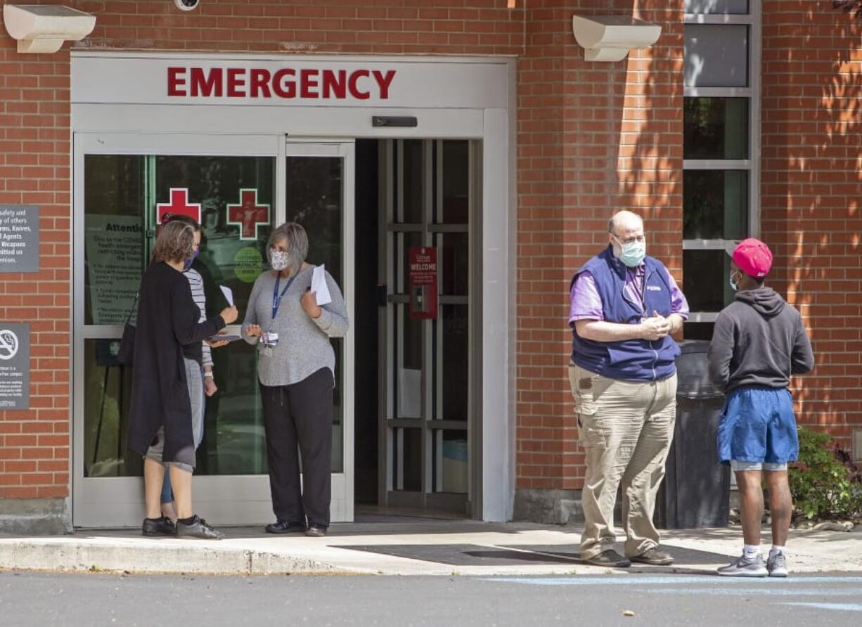 FILE - In this Tuesday, June 30, 2020, file photo, employees screen visitors for COVID-19 before they enter the building at Gritman Medical Center in Moscow, Idaho. A new spike in cases, however, has turned the mostly rural state into a COVID-19 hotspot.