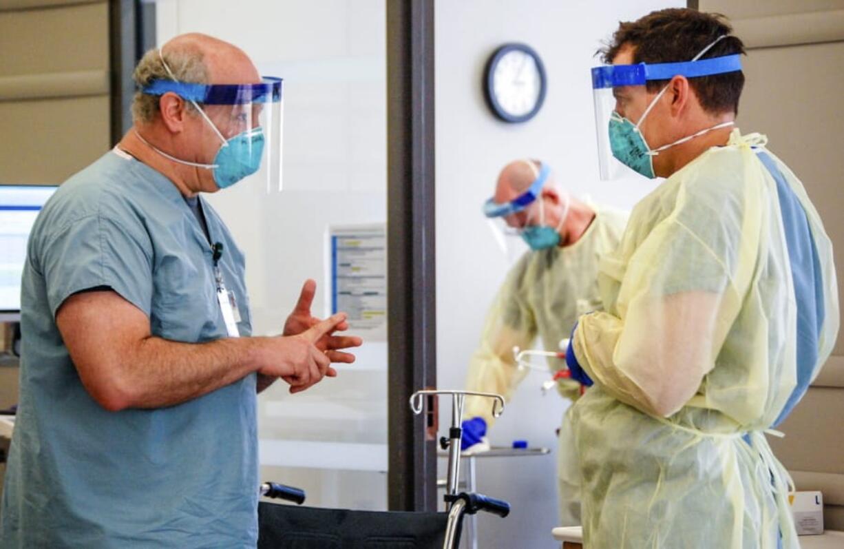 Dr. Michael Saag, left, speaks with an unidentified coworker in Birmingham, Ala., on Friday, July 10, 2020. Saag survived COVID-19 and now treats patients with the disease.