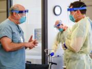 Dr. Michael Saag, left, speaks with an unidentified coworker in Birmingham, Ala., on Friday, July 10, 2020. Saag survived COVID-19 and now treats patients with the disease.