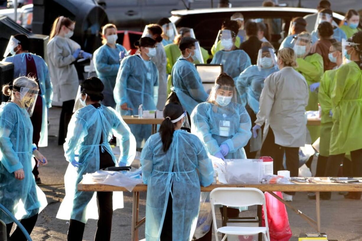 FILE - In this June 27, 2020, file photo, medical personnel prepare to test hundreds of people lined up in vehicles in Phoenix&#039;s western neighborhood of Maryvalefor free COVID-19 tests organized by Equality Health Foundation, which focuses on care in underserved communities. The personal protective gear that was in dangerously short supply during the initial weeks of the coronavirus crisis in the U.S. is running out again as the virus resumes its rapid spread and the number of hospitalized patients climbs.