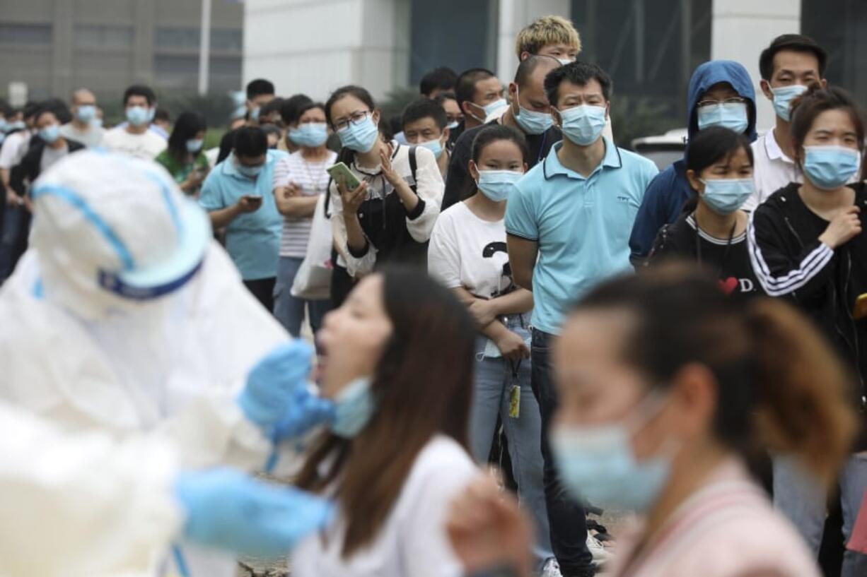 People line up May 15 for coronavirus testing at a large factory in Wuhan in central China&#039;s Hubei province. In June, China reported using batch testing as part of a recent campaign to test all 11 million residents of Wuhan.