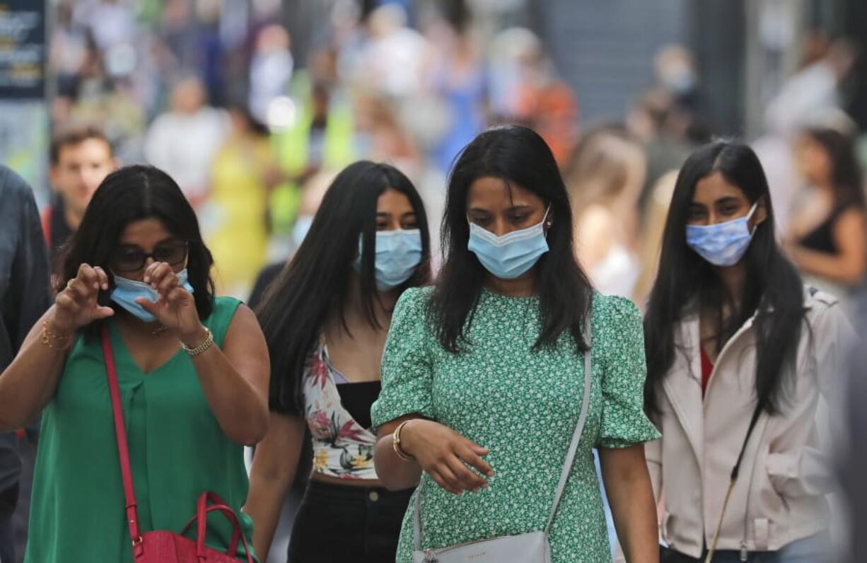 Shoppers wear face coverings to protect themselves from COVID-19 as they walk along Oxford Street in London, Friday, July 24, 2020. New rules on wearing masks in England have come into force, with people going to shops, banks and supermarkets now required to wear face coverings. Police can hand out fines of 100 pounds ($127) if people refuse, but authorities are hoping that peer pressure will prompt compliance.