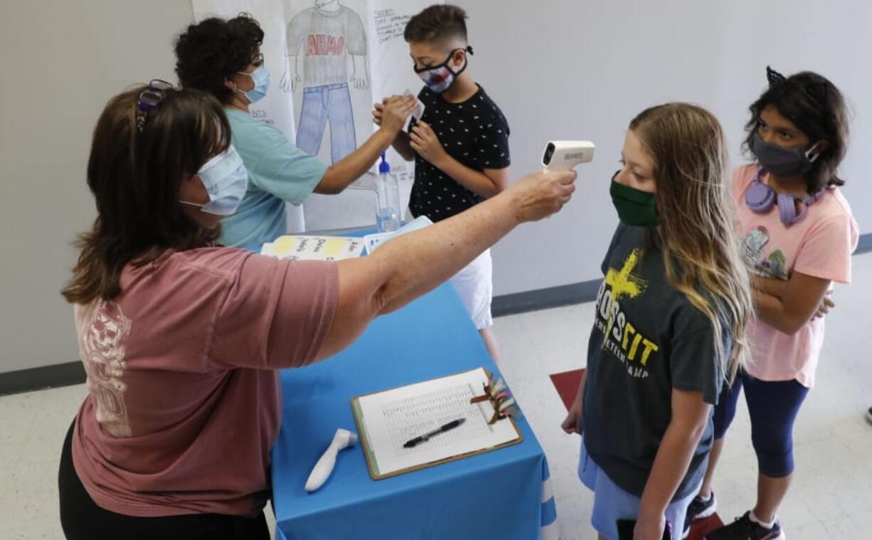 FILE - In this Tuesday, July 14, 2020 file photo, Amid concerns of the spread of COVID-19, teachers check students before a summer STEM camp at Wylie High School in Wylie, Texas. Not knowing if children are infected makes it difficult for schools to reopen safely, many experts say. Scarce data on whether infected children -- including those without symptoms -- easily spread the disease to others complicates the issue, said Jeffrey Shaman, a Columbia University infectious disease specialist.